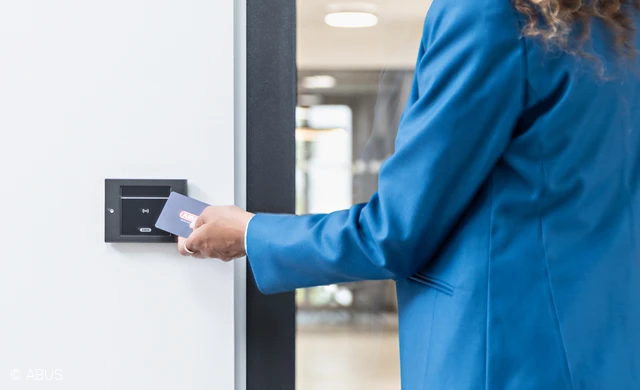 A woman reads her card with access authorisations at the TECTIQ wall reader.